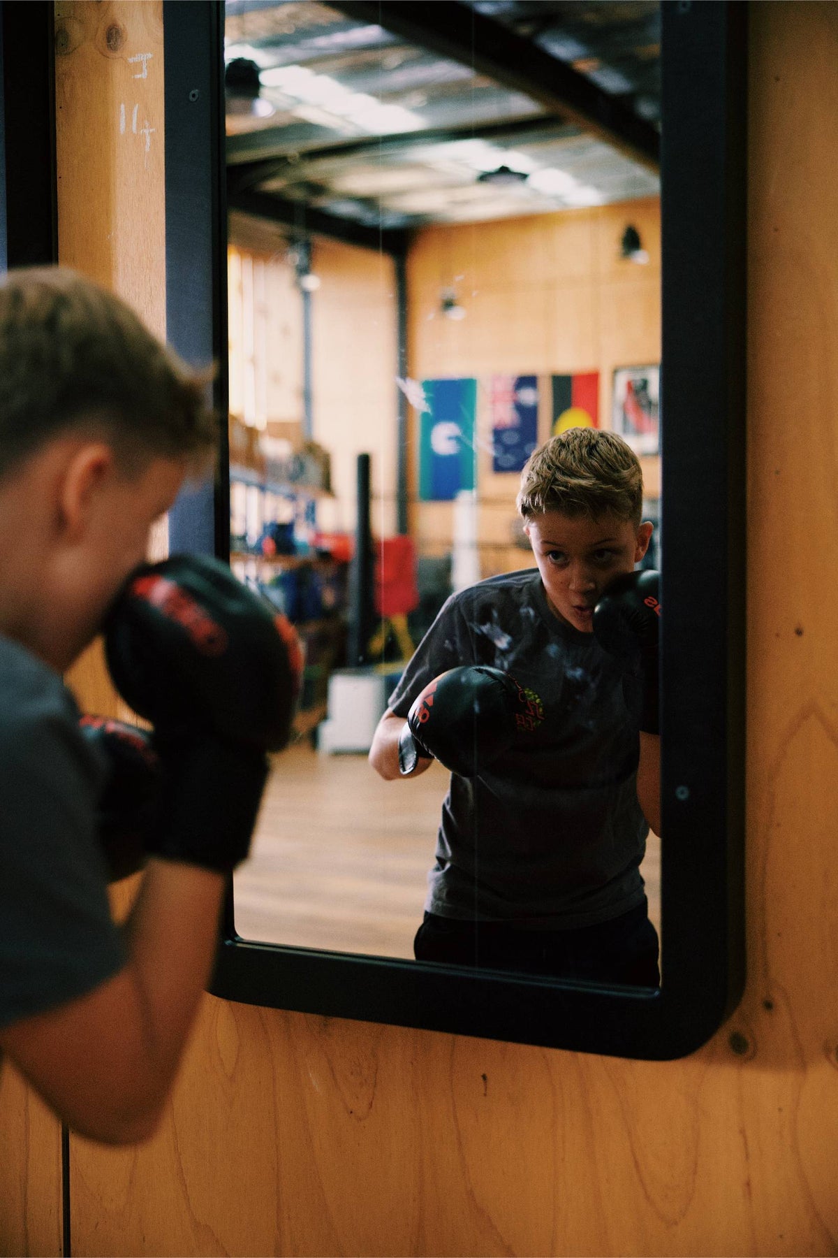 Combat Mirror in use at a boxing gym, training in front of the wall-mounted mirror.