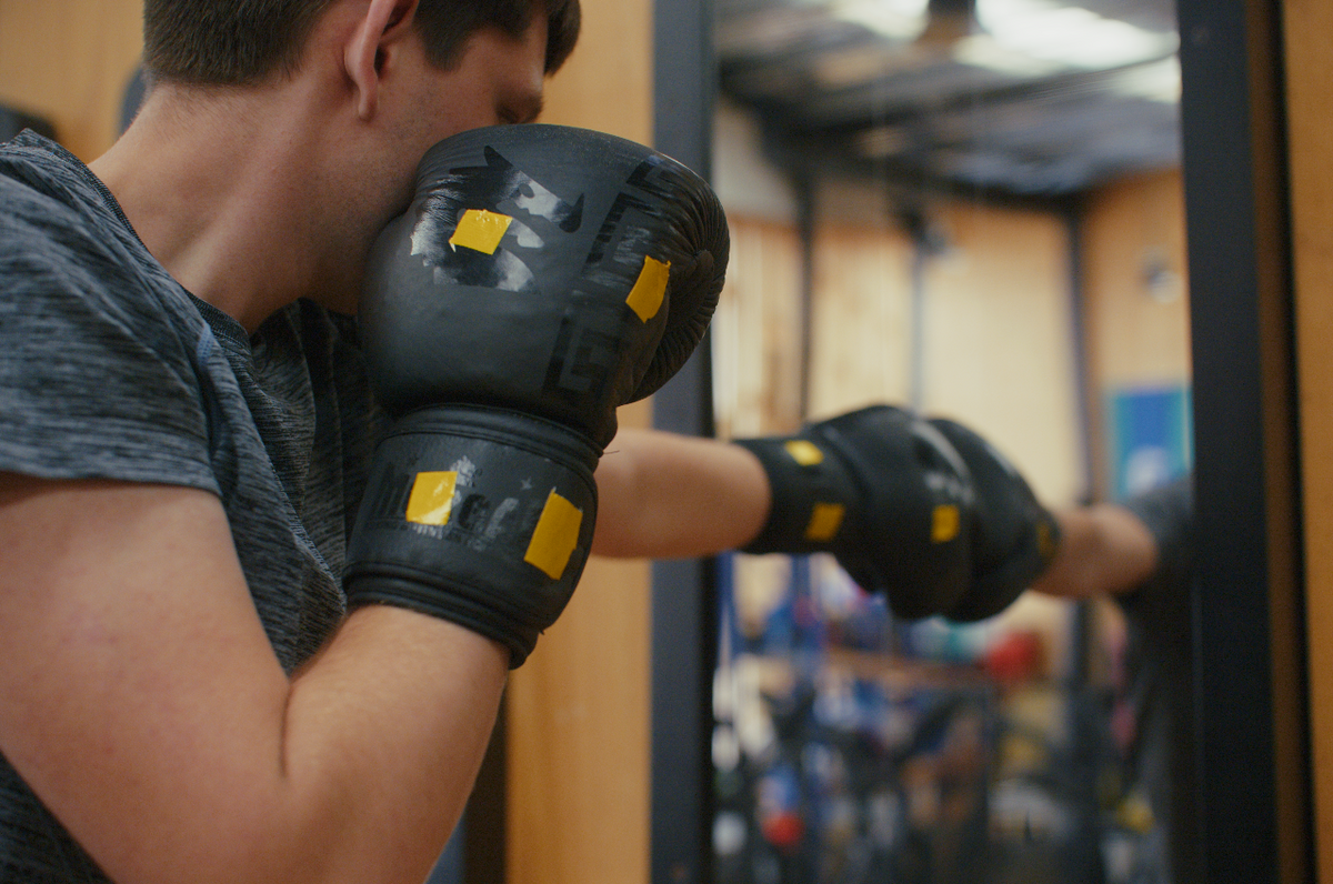 Combat Mirror in use at a boxing gym, training in front of the wall-mounted mirror.