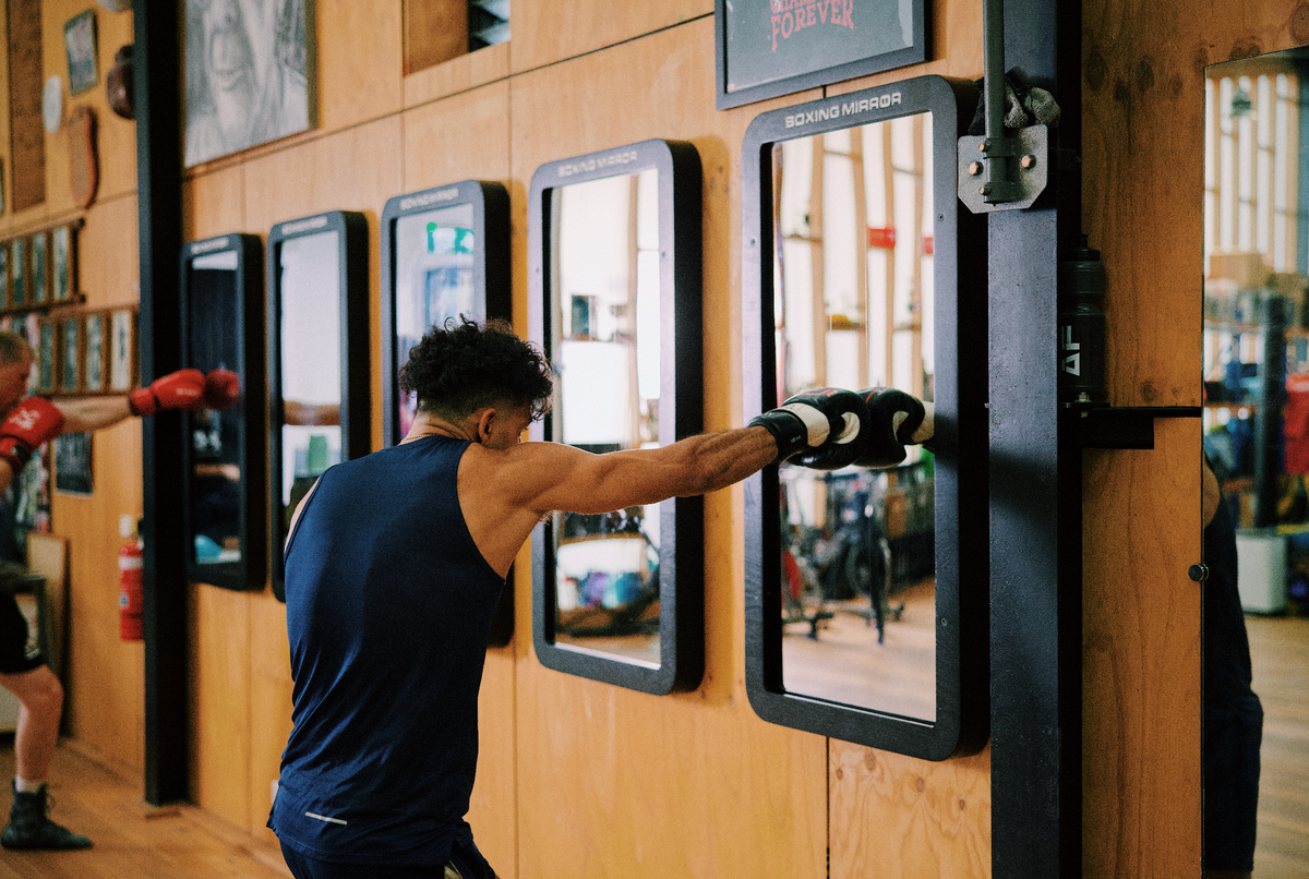 Combat Mirror in use at a boxing gym, training in front of the wall-mounted mirror.