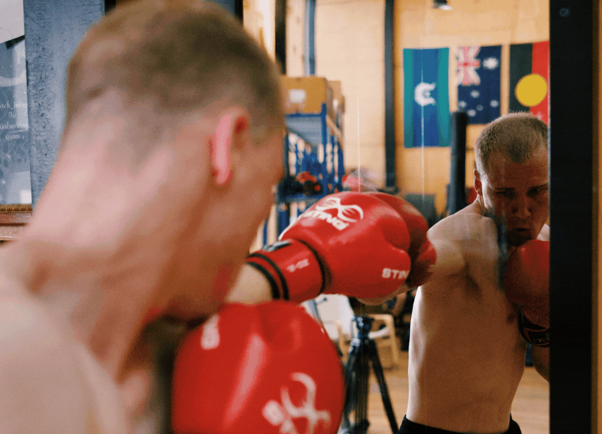 Combat Mirror in use at a boxing gym, training in front of the wall-mounted mirror.